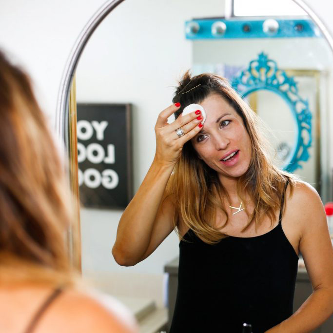 a mulher usando um algodão redondo na face 